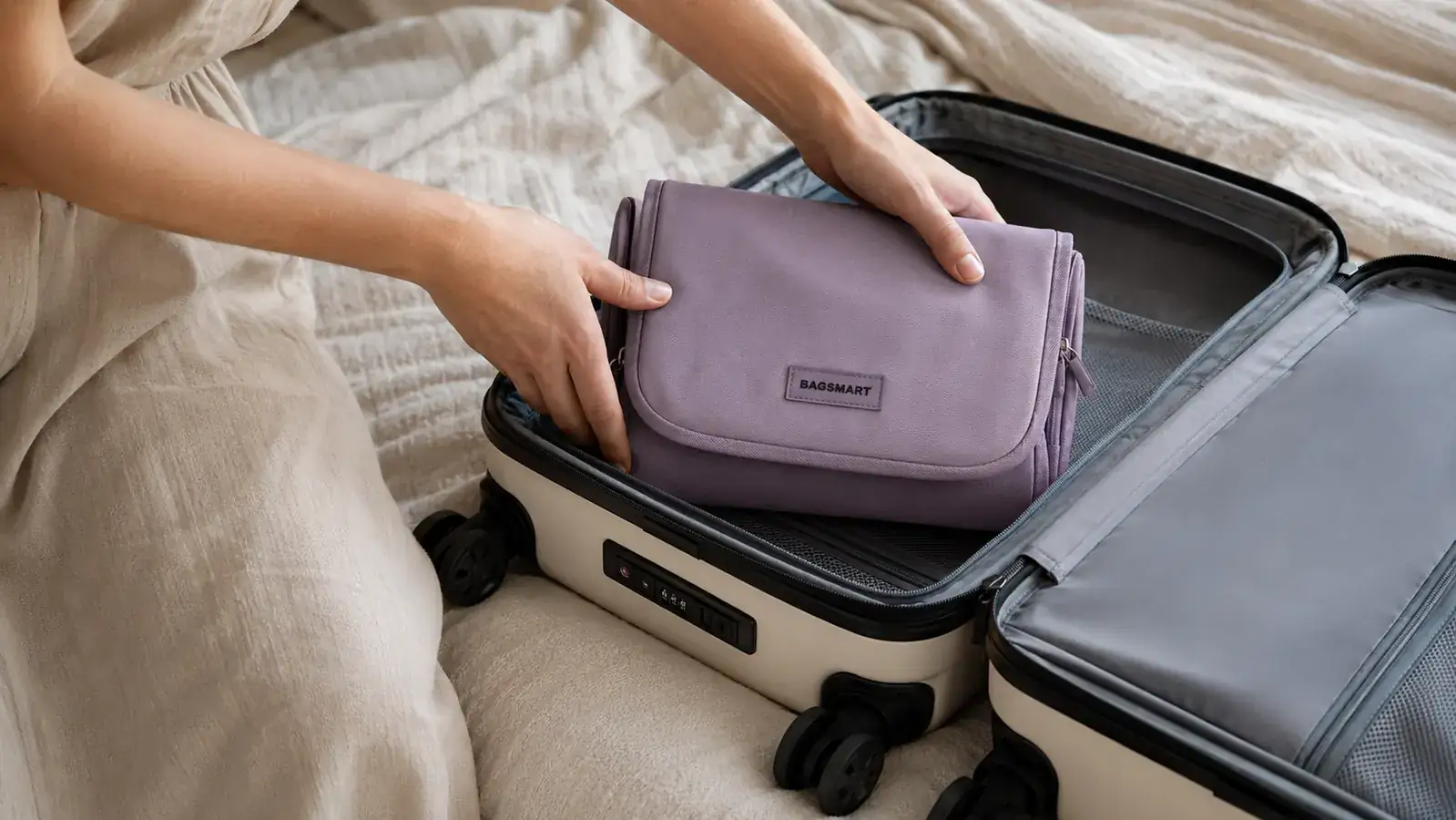 Traveler zipping up the BAGSMART toiletry bag before placing it into a carry-on suitcase