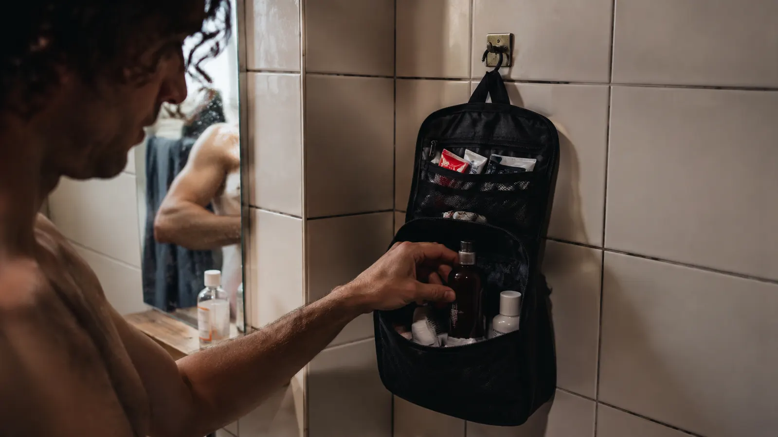 BAGSMART toiletry bag hanging from a cramped hostel bathroom hook with toiletries accessible without touching the floor