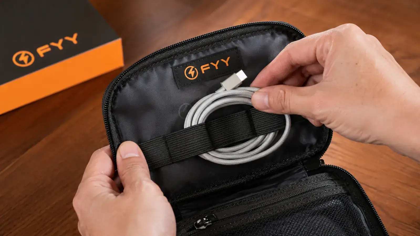 Hands placing a coiled USB-C cable into the elastic loops inside a travel cable organizer pouch