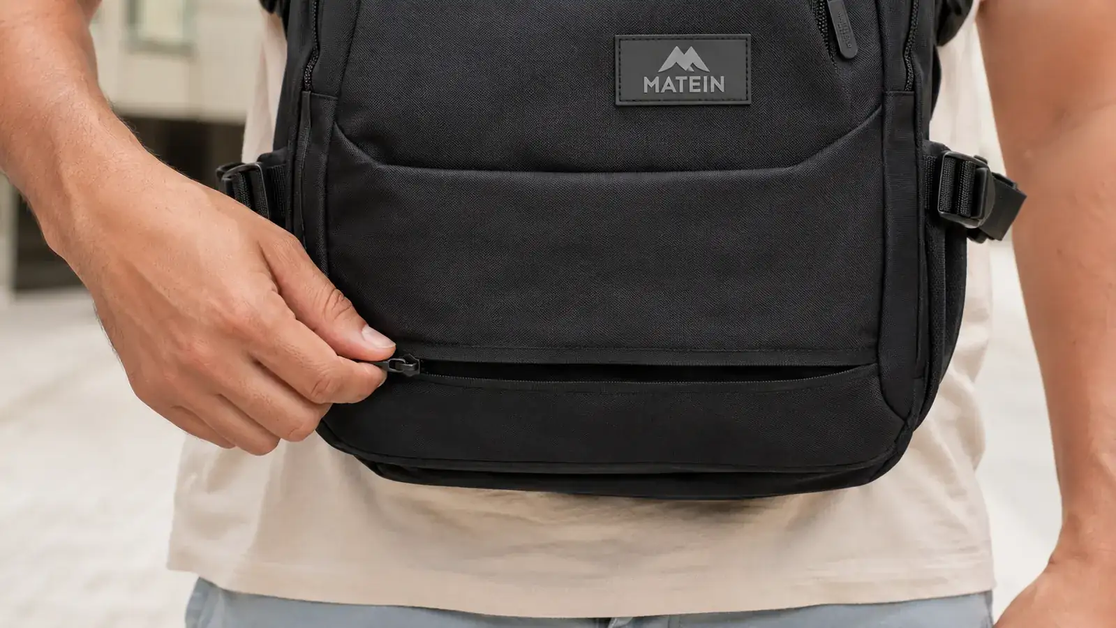 Close-up of a hidden back zipper on a dark travel backpack pressed against a body
