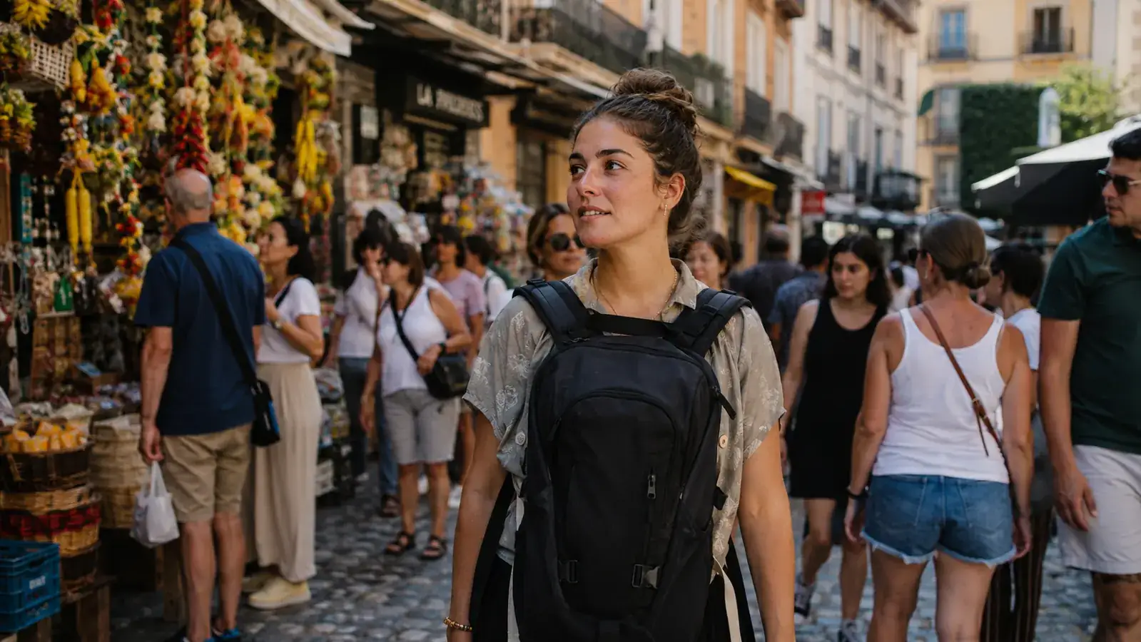Traveler carrying the MATEIN backpack through a busy European street market, backpack worn on front for security