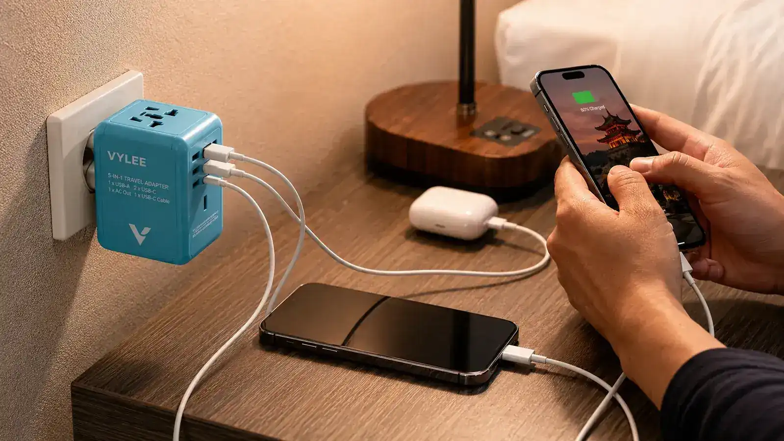 VYLEE universal travel adapter plugged into a Japanese Type-A outlet with two USB-C cables and one USB-A cable attached
